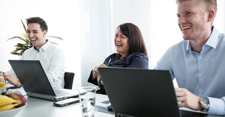 people in front of laptops laughing in a meeting